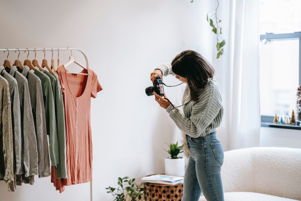 Women standing with a camera taking photos of clothes.