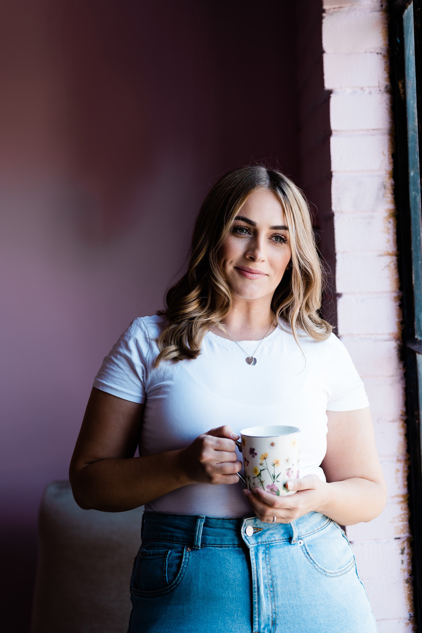 Steph Honey, host of 'The Brand Essentials' podcast, Episode #1: 'The Truth About Branding', poses with a charming smile, holding a floral mug, embodying a blend of professionalism and approachability, perfect for creative entrepreneurs seeking branding insights.
